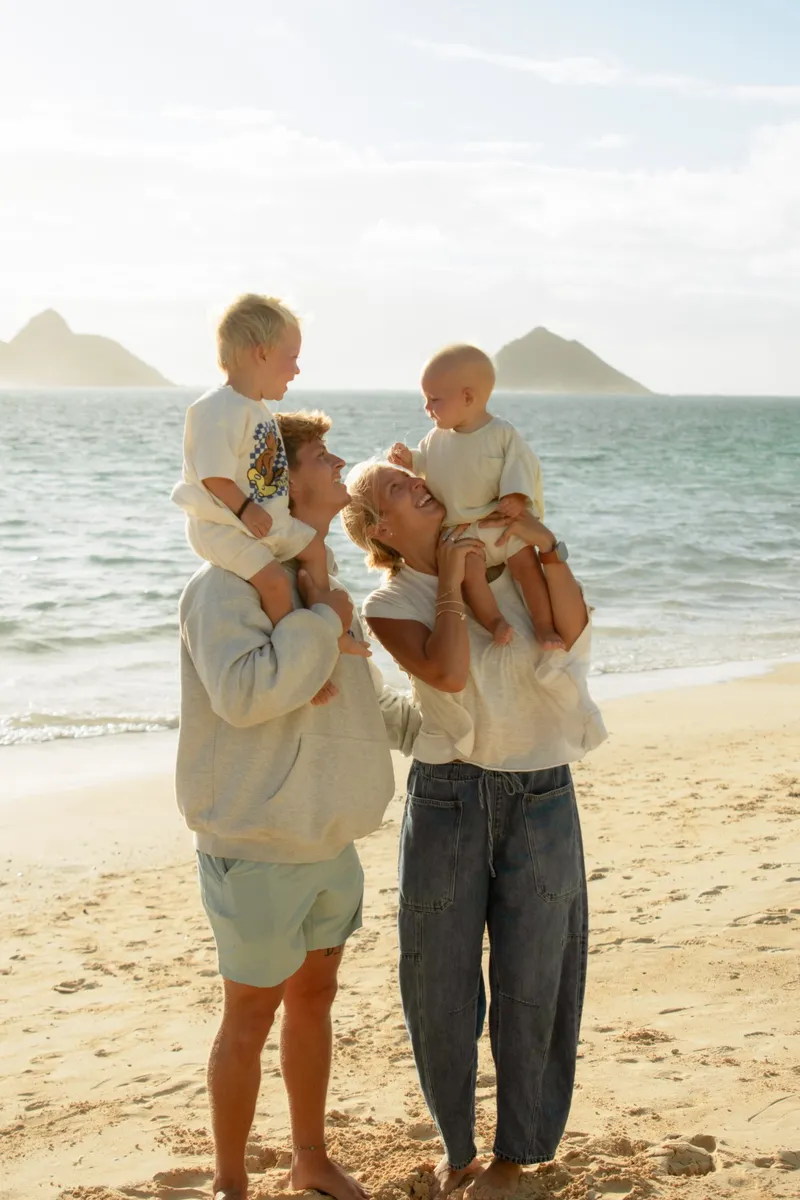 Clay and Ali on the beach, each with one of their two boys on their shoulders