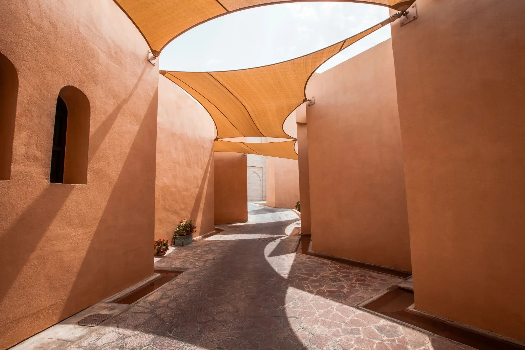 Sunlit terracotta courtyard under shade sails